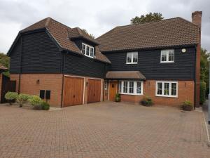 a large black house with a large driveway at Fly By in Duxford