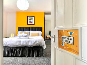 a bedroom with a large bed with a yellow wall at Merseybeat Short stays in Birkenhead