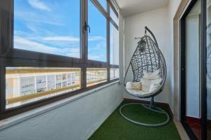 a hanging chair in a room with a window at Aiyra Beach House in Costa da Caparica