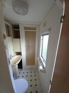 La salle de bains est pourvue d'un lavabo, de toilettes et d'une fenêtre. dans l'établissement Vakantiechalet B6, à Makkum