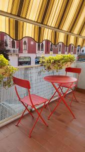 2 sillas rojas y una mesa en el balcón en B&B Velocipede, en Cervignano del Friuli