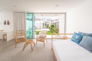 een woonkamer met een bed en stoelen en een balkon bij Oceanside West in Ponta Delgada