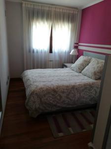 una camera da letto con un grande letto con una parete rosa di Apartamento El Ferial a Sarón