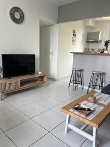 a living room with a television and a table at Logement 10 minutes de rouen in Oissel