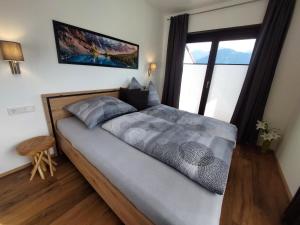 a bedroom with a large bed with a large window at Dolomitenhome Apartments in Patriasdorf