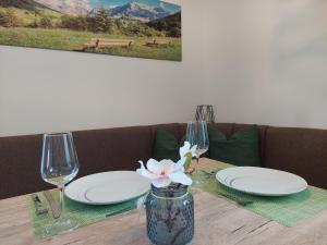 a table with plates and glasses and a flower in a vase at Dolomitenhome Apartments in Patriasdorf