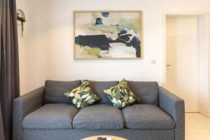 a blue couch in a living room with a painting at Lennox Beautiful 2 Bed in Accra