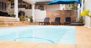 een groot zwembad met stoelen en een parasol bij Casa Maria in Port Louis