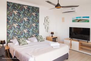 1 dormitorio con 1 cama grande y TV en Casa Maria en Port Louis