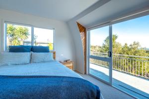 ein Schlafzimmer mit einem blauen Bett und einem großen Fenster in der Unterkunft The Round House in Oneroa