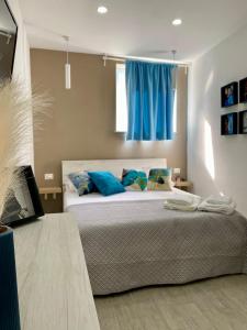 sypialnia z łóżkiem z niebieskimi poduszkami i oknem w obiekcie La casetta di Marianna w mieście Napoli