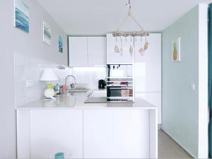 Una cocina blanca con gabinetes blancos y un fregadero. en Magnifique 4 COUCHAGES FRONT MER, en Menton