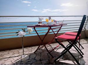 una mesa y una silla en un balcón con vistas al océano en Magnifique 4 COUCHAGES FRONT MER, en Menton