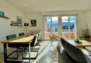 ein Wohnzimmer mit einem Tisch und Stühlen sowie einem großen Fenster in der Unterkunft Toit-terrasse traversant plein centre 100m du lac in Annecy