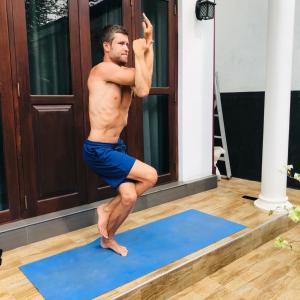 a man doing a yoga pose on a blue yoga mat at Dimuthu Vila in Wadduwa