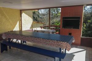 una mesa de cristal en un patio con TV en Chácara do Sapé, en São José dos Pinhais