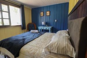 um quarto com paredes azuis e uma cama grande em Chácara do Sapé em São José dos Pinhais