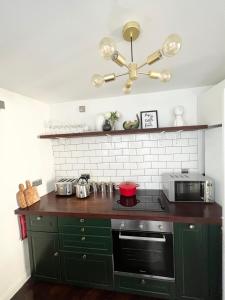 a kitchen with green cabinets and a stove top oven at Luxury Belfast Stay - Townhouse in Belfast