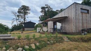 een klein houten huis met een schuur in een veld bij Orlická přehrada Chata Malá in Kožlí u Orlíka