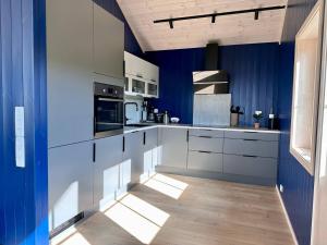 cocina con armarios blancos y paredes azules en Tors Cabin at Haukland Beach, en Offersøya