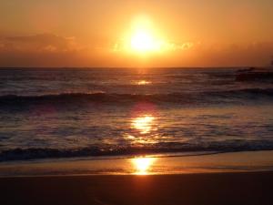 una puesta de sol en la playa con el océano en Hotel Izukyu en Shimoda