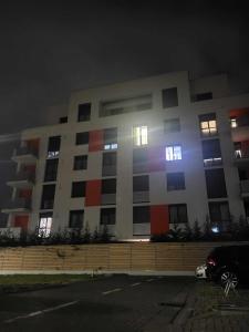 un gran edificio por la noche con un coche aparcado delante en Sika Majestic Apartment en Arad