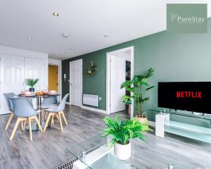 a living room with a table and chairs and a tv at Stunning Two Bed Apartment By PureStay Short Lets & Serviced Accommodation Manchester With Free Parking & WiFi in Manchester