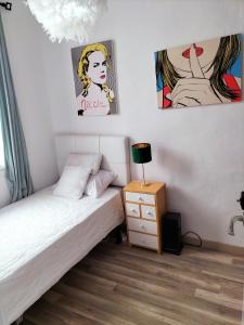 a bedroom with a bed and a nightstand and paintings at El Coqueto de Vallecas in Madrid