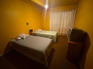 a yellow room with two beds and a television at Hospedaje Rios in Osorno