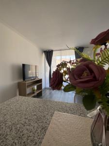 a living room with a vase of flowers and a television at Departamento Lynch Iquique in Iquique