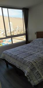 a bedroom with a bed and a large window at Departamento Lynch Iquique in Iquique