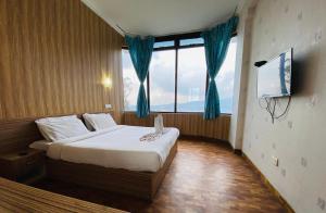 a bedroom with a bed and a large window at Tulips Resorts - Elkhill in Ooty