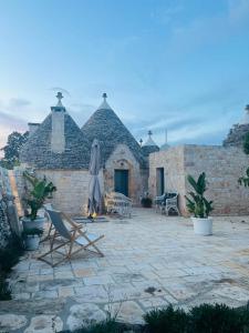 um pátio com cadeiras e um guarda-sol e um edifício em Scardino Trulli em Locorotondo