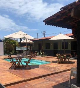 a patio with tables and umbrellas next to a pool at Pousada Fragata in Porto De Galinhas