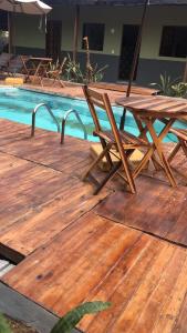 a wooden deck with a table and chairs next to a pool at Pousada Fragata in Porto De Galinhas