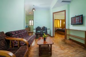 a living room with couches and a table and a tv at Tulips Resorts - Elkhill in Ooty