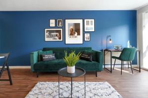 a living room with a green couch and a blue wall at Stylish Apartment - Walking Distance to the City Centre - Free Parking, Fast Wi-Fi and SmartTV with Netflix by Yoko Property in Coventry