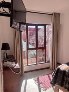 a bedroom with a large window and a desk with a phone at VIRREYES HOTEL in Potosí