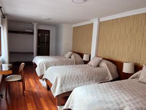 a hotel room with three beds and a table at VIRREYES HOTEL in Potosí