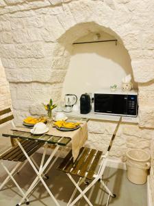 eine Küche mit einem Tisch und einer Mikrowelle in der Unterkunft Scardino Trulli in Locorotondo