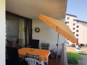 上斯陶芬的住宿－Schöne 2 1/2 Zimmer Ferienwohnung in Oberstaufen - Hoamatle -，庭院里摆放着橙色的桌子和椅子,配有遮阳伞