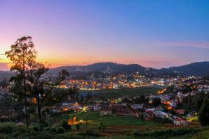 una vista de la ciudad por la noche con la puesta de sol en Tulips Resorts - Elkhill en Ooty