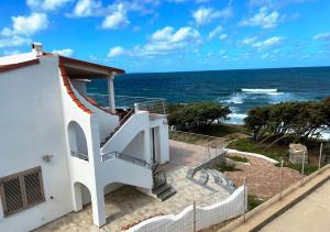 una casa blanca con escaleras que conducen al océano en TITINO stupendo appartamento in villa fronte Mare - Golfo dell'Asinara - Internet Free, en Codaruina