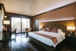 a hotel room with a large bed and a large window at Maneechan Resort - SHA Extra Plus in Chanthaburi