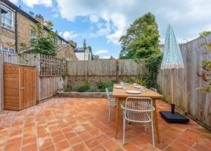 a patio with a wooden table and chairs and a fence at Gorgeous Garden Apartment *Cafes/Bars/Beach within minutes* in Kent