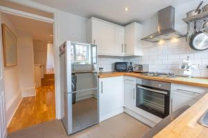 a kitchen with white cabinets and a stove top oven at Gorgeous Garden Apartment *Cafes/Bars/Beach within minutes* in Kent
