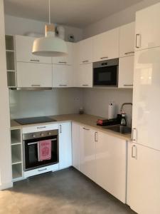 a kitchen with white cabinets and a stove top oven at Chopin airport Apartment in Warsaw