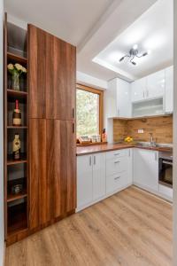 a kitchen with white cabinets and a wooden door at Apartman Gačanović Lux in Zlatibor