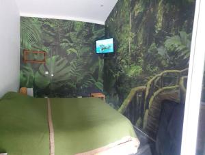 a bedroom with a jungle themed room with a bed and a television at La chambre émeraude in Fayence