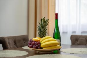 a plate of fruit on a table with a bottle of wine at Apartman Gačanović Lux in Zlatibor +35 photos